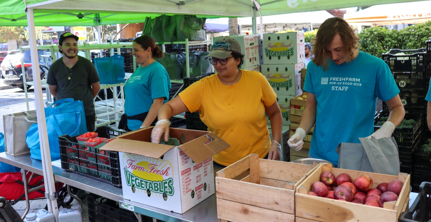 The Pop-Up Food Hub Staff packing bags of produce at a farmers market s